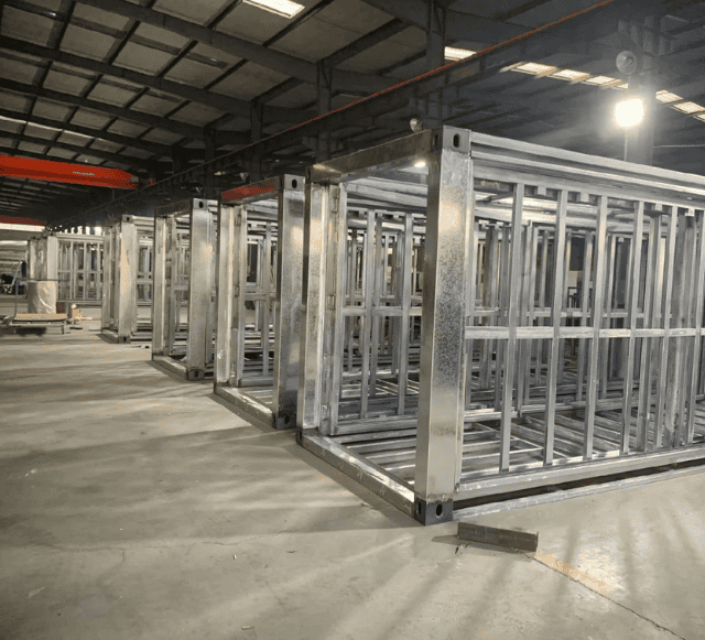 Factory view of prefabricated steel frames stacked in rows, ready for assembly into modular buildings.