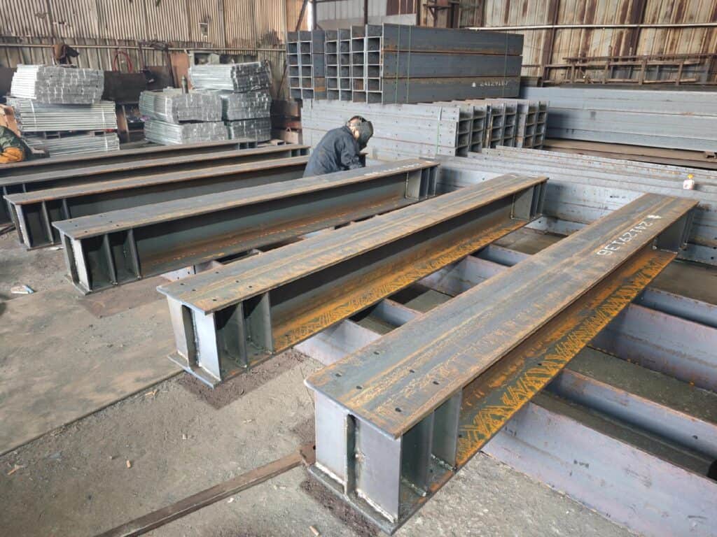 Prefabricated steel beams in a factory setting, ready for construction use.