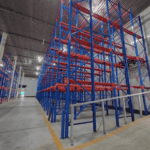 Interior of a Cold Storage Building with blue and red metal shelving units, ready for storing goods, under a metallic ceiling.