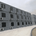 Large complex of stacked container barracks with uniform air conditioning units, showcasing a functional and scalable housing solution.