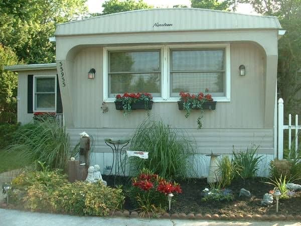 Cozy mobile home with front garden, flower boxes, and decorative landscaping