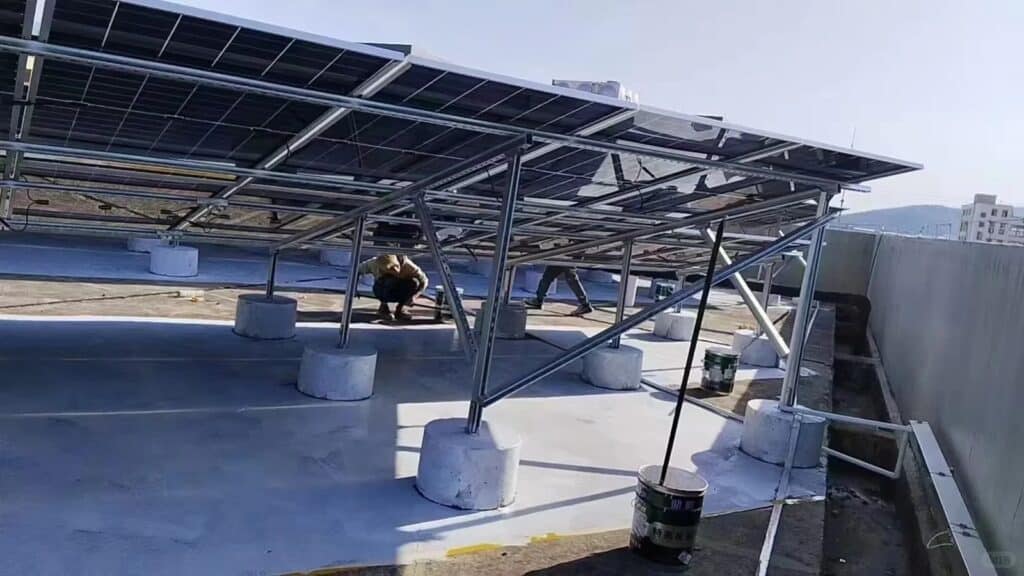 Flat rooftop solar mounting system installation with concrete ballast foundation and workers assembling photovoltaic panels