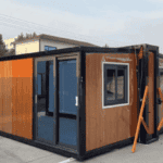 A wooden-panel folding container house with large glass doors and windows, displayed outside in a modern setup.