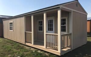 A beige gable - roof portable cabin with a small porch, featuring multiple windows and a central door.