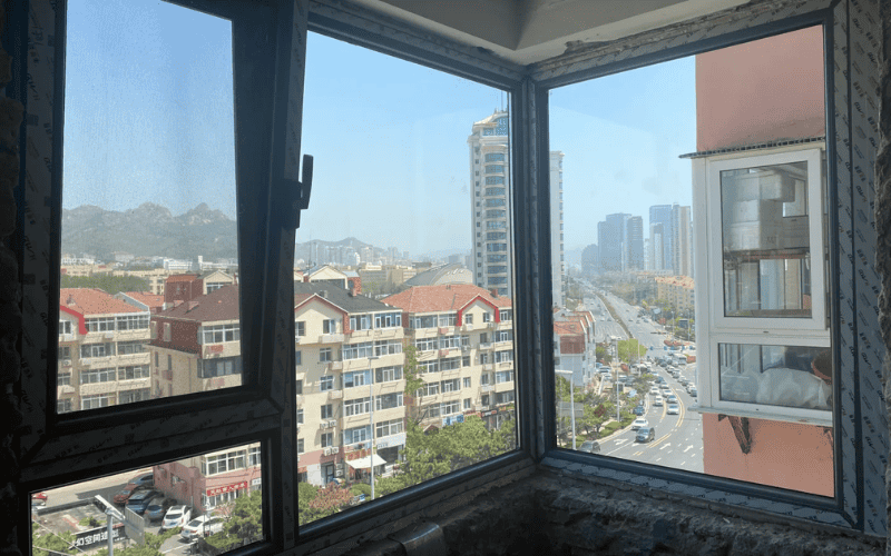 Panoramic view through newly installed windows, overlooking urban residential and commercial buildings.