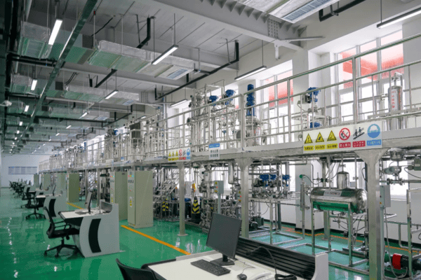 An advanced factory interior with metal pipes, green flooring, and modern machinery.