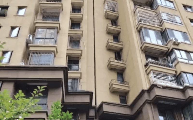 High-rise residential building facade with multiple balcony styles and enclosed window installations.