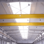 Interior of a Metal Structure Barn Building with yellow overhead cranes, white walls, and a ceiling featuring skylights and multiple lights.