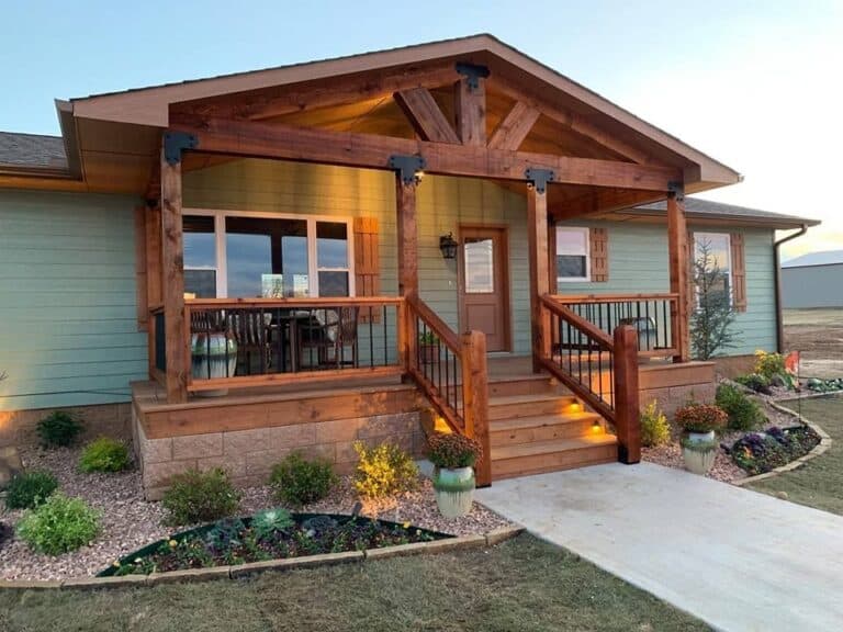 Manufactured home with a craftsman-style front porch, wooden columns, and landscaping that gives it the look of a traditional house