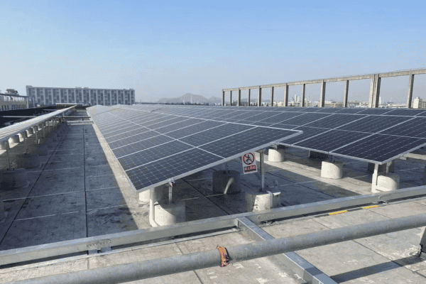 Solar panels installed on steel photovoltaic brackets on a rooftop under a clear blue sky.