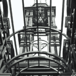 An interior view looking up at the steel framework of a Prefab Steel Church Building, showcasing its tall clock tower and detailed arch designs.