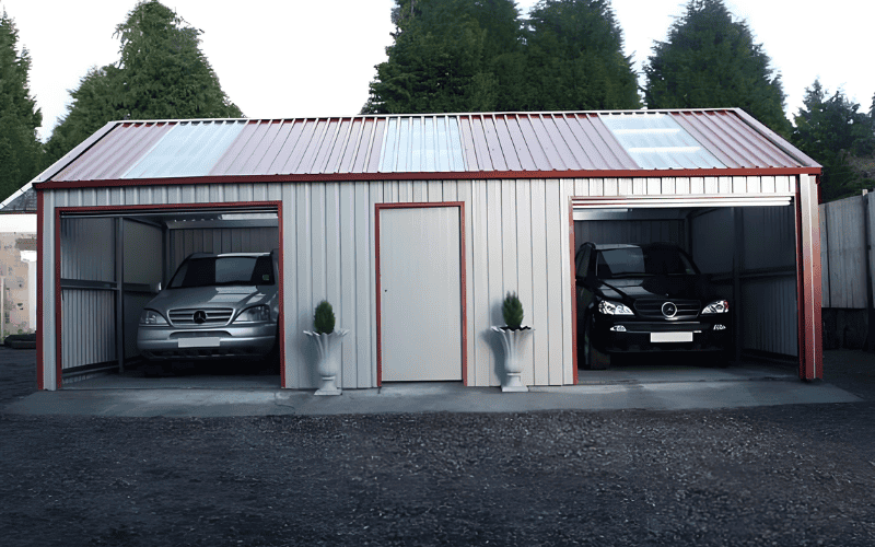 A prefab steel garage with open bays, housing two cars and a central door.