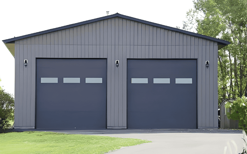 A modern prefab steel garage with grey siding and two large doors.