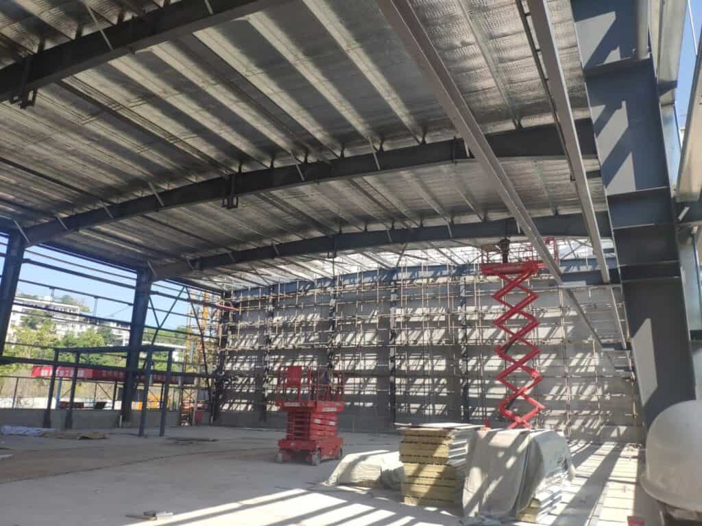 Interior view of a steel - framed building with its steel roof system under construction.