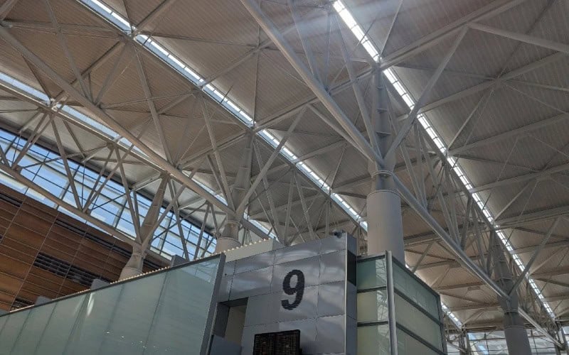 Large - scale steel roof trusses in a building, with natural light coming through the skylights.