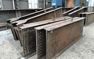 Factory scene with multiple steel structure beams laid out for processing.