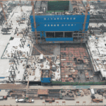 Bird's-eye perspective of a Steel Structure Multi-Storey Building in progress, showing blue construction banners, steel beams, and concrete foundations.