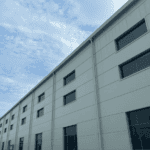 A completed Steel Structure Office Building with a sleek white exterior and multiple windows under a partly cloudy sky.