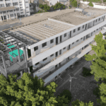 Aerial view of a completed part of the Steel Structure School Building, connected to an existing structure, surrounded by greenery.