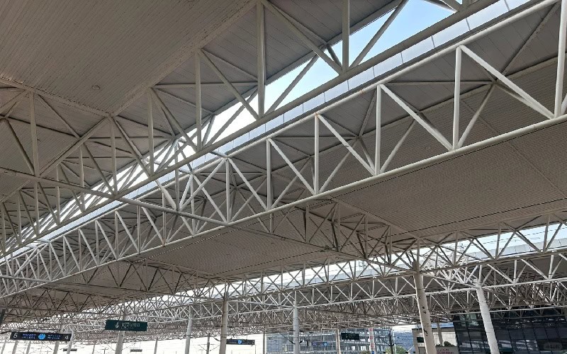 Interior view of a large - scale steel truss system used in a building roof.