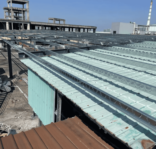 Steel structure construction - A steel-framed roof structure being installed, with translucent green roofing sheets partially covering the framework.