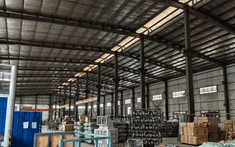 A spacious steel warehouse with insulation panels, organized inventory, and proper lighting.