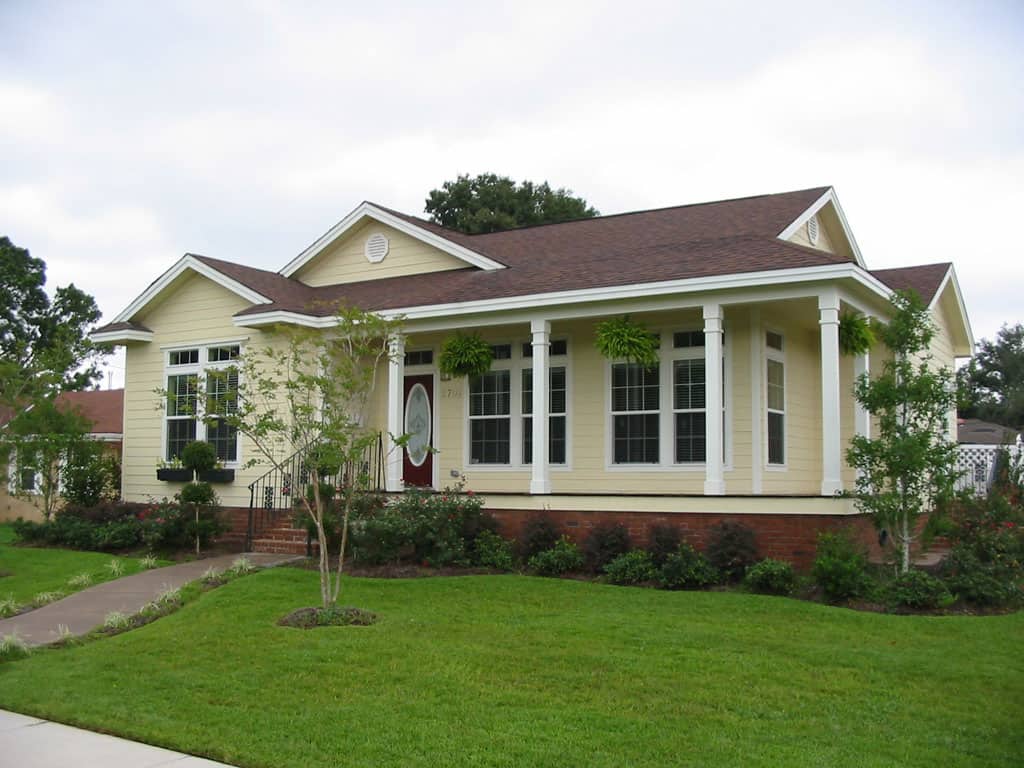 Stylish manufactured home with front porch, gabled roof, and landscaped yard