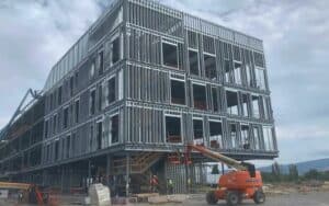 Under - construction steel building with structural framework visible.