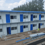 A two-story Temporary Modular Building featuring blue and white exteriors, several doors, and windows, under construction outdoors with building materials around.