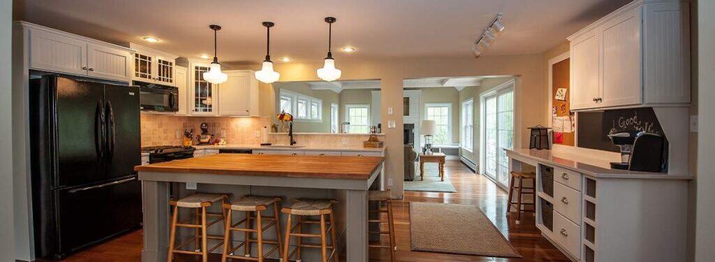 Warm and inviting modular home kitchen with wood countertops, pendant lighting, and open layout connecting to a bright living space