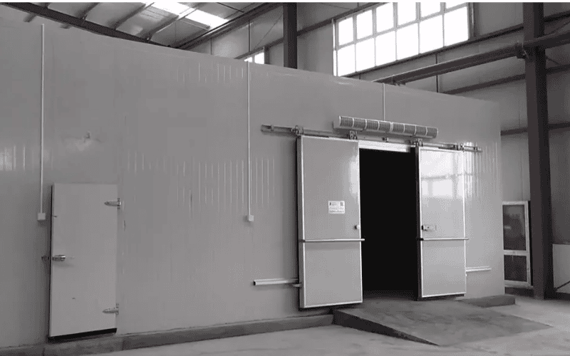 A cold storage facility with a metal door and insulated walls, designed to maintain low temperatures.