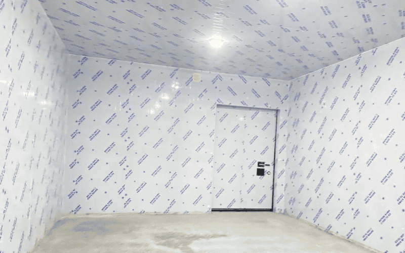 A close-up of a cold storage room with clean, insulated walls and a large door with a lock, ready for storage.