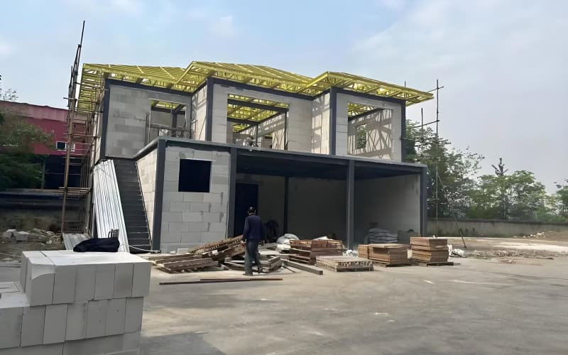 Two - story prefab building under construction with steel frames and block walls.