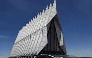 A modern church with a striking angular design, featuring triangular steel and glass panels, set against a clear blue sky.