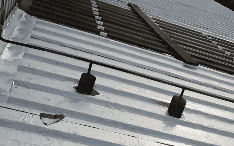 A close-up view of a metal roof with newly installed black brackets and fasteners for reinforcement and repair.