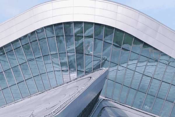 A close-up view of a modern building facade with curved glass panels reflecting the surroundings.