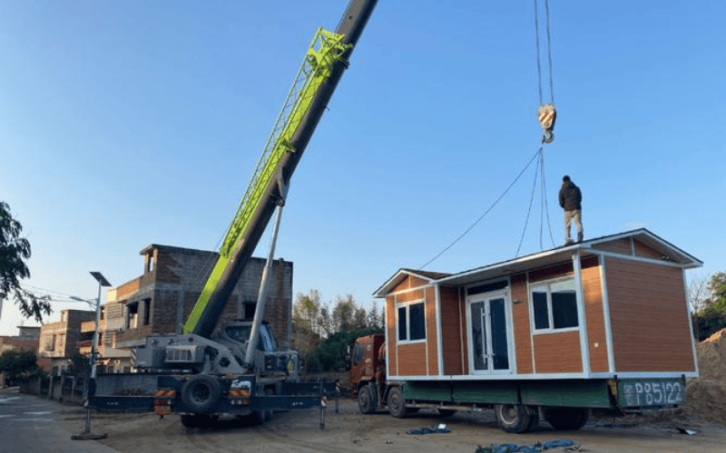 A modular home lifted and placed into position with the help of a crane, demonstrating the ease of assembly for prefabricated homes.