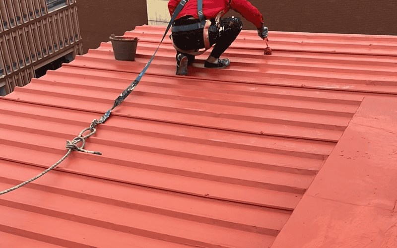 worker painting a steel roof panel