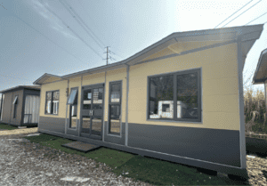 A yellow and gray modular home with large windows and a modern door, offering a bright and spacious exterior.
