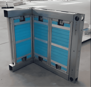 Ein modularer Wandrahmen mit blauen Paneelen, der eine Eckkonstruktion mit Metallrahmen zeigt, bereit zur Montage in einer Fabrikumgebung.