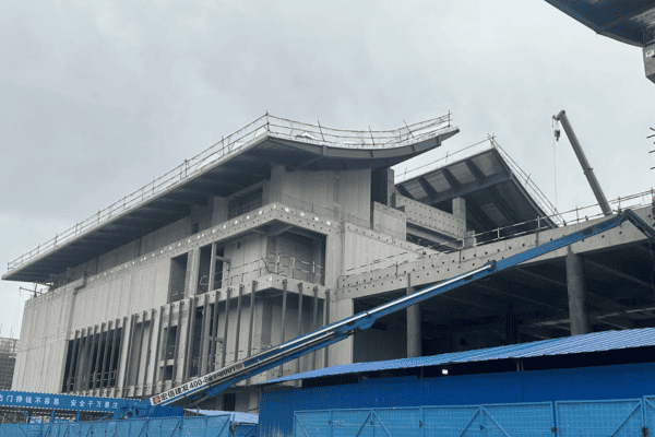 A concrete and steel building under construction with a unique architectural design and scaffolding in place.