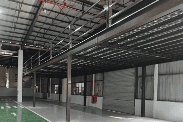 A steel mezzanine platform under construction inside a warehouse, featuring a partially completed floor.