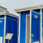 Blue portable restroom units with open doors, placed side by side in a bright outdoor setting.