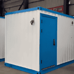 A blue and white container-style restroom block with a metal door and windows, placed in an industrial setting.