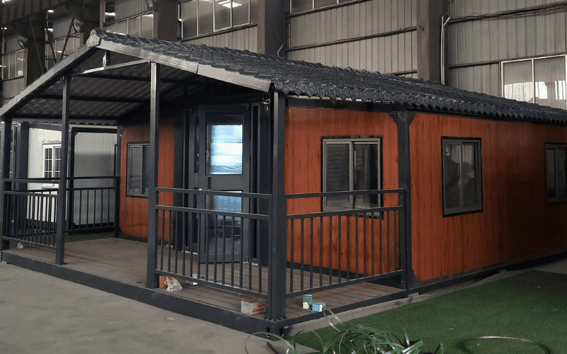 A modular home with a stylish wood-paneled exterior, featuring large windows and a porch with a metal railing, giving it a modern look.