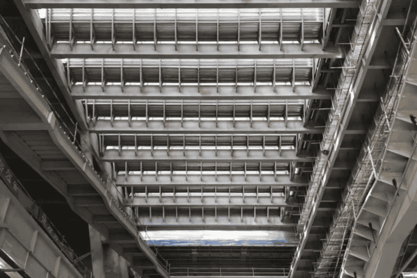 An industrial steel framework with skylights above, showcasing intricate structural details.