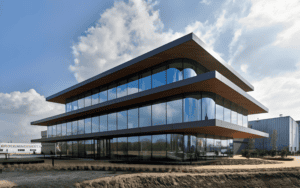 Modern sound insulation steel building with sleek design, large glass - paned windows, and multiple floors under a partly cloudy sky.