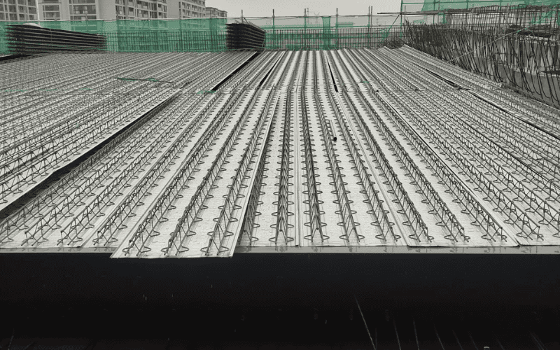 A steel deck with evenly spaced reinforcements, forming the base of a composite floor system in a high-rise building under construction.