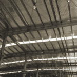 An interior view of a large metal barn, showcasing reflective insulation and industrial lights on the ceiling.