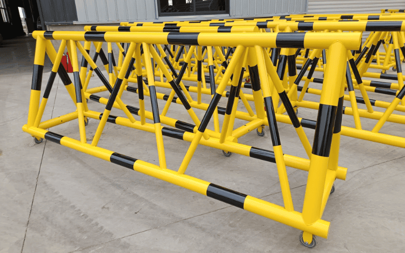 Yellow-painted steel truss barriers with black safety stripes, designed for industrial or construction zone safety.